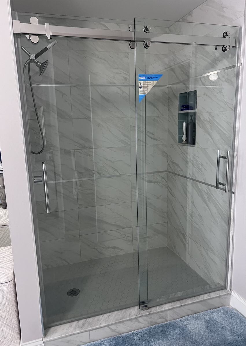 Frameless double sliding shower doors with chrome hardware